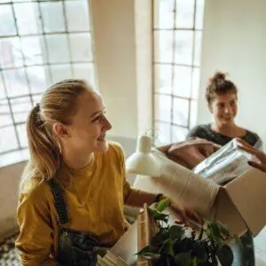 2 étudiantes qui déménagent, elles ont des cartons dans les bras mais semblent joyeuses