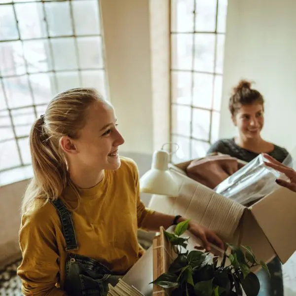 2 étudiantes qui déménagent, elles ont des cartons dans les bras mais semblent joyeuses