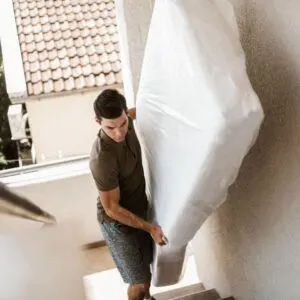 homme qui monte un matelas dans des escaliers